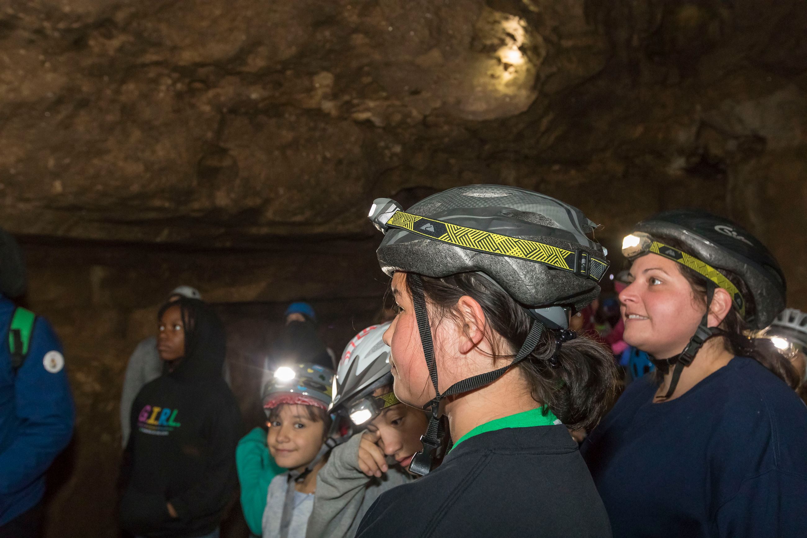 Girls wearing helmets and headlamps in a cave.